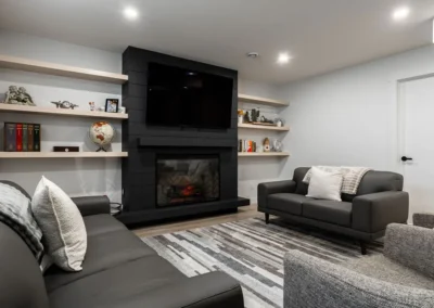 contemporary basement lounge with leather sofa and black shiplap fireplace by Saskatoon basement developer Axium Interiors